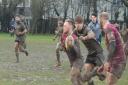 Hitchin's Will Evans makes inroads through the mud against Finsbury Park.