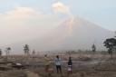 Villagers stand on an area covered in volcanic ash from Mount Semeru
