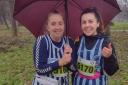 Sharon Crowley and Molly Crimmin of Fairlands Valley Spartans shelter under an umbrella at the county champs.