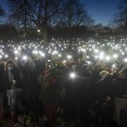 People in the crowd turn on their phone torches as they gather in Clapham Common, London, after the Reclaim These Streets vigil for Sarah Everard was cancelled
