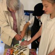Hexton JMI pupils with Mrs Yvonne Limbrick, former head of the school, cutting a cake to commemorate its 175th anniversary