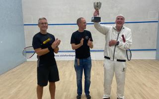 Patrick St Leger (right) holds the trophy aloft after winning his final squash tournament before retiring from the sport.